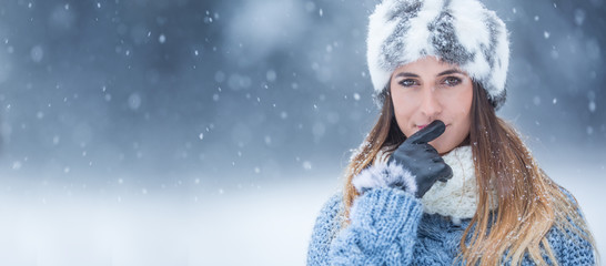 Portrait of young beautiful woman in winter clothes and strong snowing.