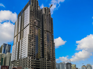 Fototapeta na wymiar Construction site, crane and big building under construction against blue cloudy sky