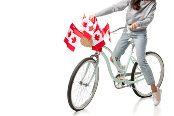 cropped view of woman riding vintage bicycle with canadian flags isolated on white