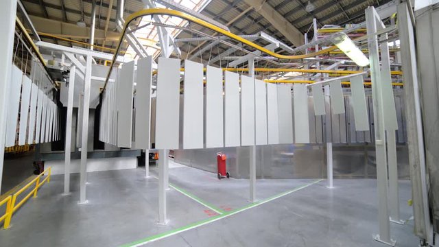 Powder coating line. Metal panels are suspended on an overhead conveyor line.