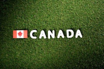 top view of word 'Canada' with canadian flag on green grass background