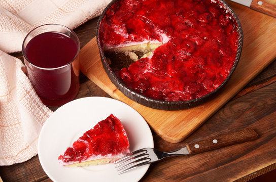 A piece of cheese cake with red jelly and berries