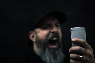 Mann mit Bart schreit Handy an