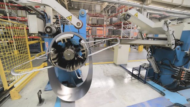 Cold rolled steel coil on decoiler of machine in metalwork manufacturing.