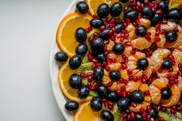 Fruit dessert. Orange, grapes, pomegranate on a white plate. Festive table.