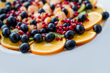 Fruit dessert. Orange, grapes, pomegranate on a white plate. Festive table.