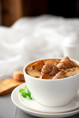 Soup with snails in a white plate.