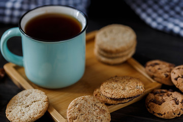 Cup of tea and various cookies on dark wooden background
