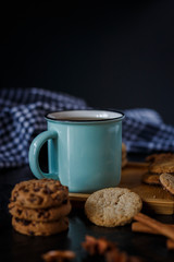 Cup of tea and various cookies on dark wooden background