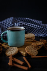 Cup of tea and various cookies on dark wooden background