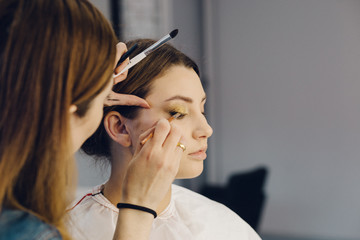 makeup artist applying eyeshadows on model's eyes. beauty fashion industry. Closeup view of an artist's hand using special brush