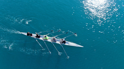 Aerial drone bird's eye view of sport canoe operated by team of young men in open sea