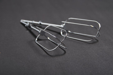 Kitchen utenstil. Metal wire whisk on dark background.