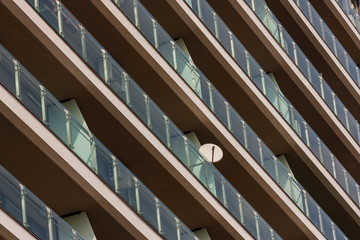 a facade of a modern building and a hanging satellite dish on one of the terraces. receiving a satellite home signal. satellite TV.