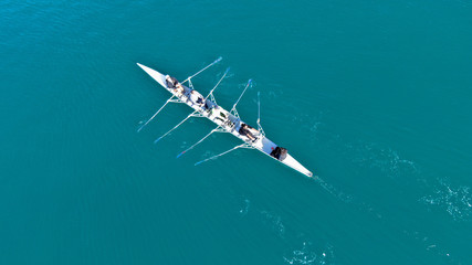 Aerial drone bird's eye view of sport canoe operated by team of young men in open sea