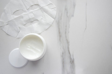 Facial mask and cream on marble table