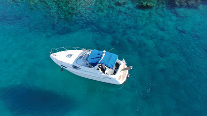 Aerial bird's eye view photo taken by drone of boat cruising in caribbean tropical beach with turquoise - sapphire waters