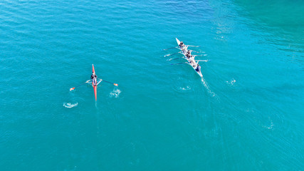 Aerial drone bird's eye view of sport canoe operated by young man in turquoise clear waters