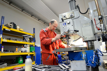 Metal construction worker operates drilling machine // Arbeiter im Metallbau bedient Bohrmaschine