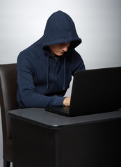 Hooded hacker at his laptop