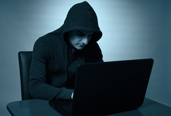 Hooded hacker at his laptop