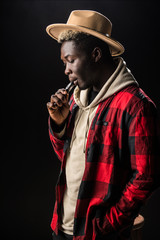 The African man smoke an electronic cigarette on the dark background