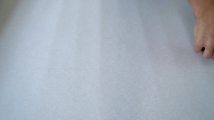 closeup male hands measure new wallpaper roll with measure tape on table indoor