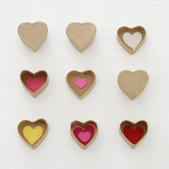 Valentine's day concept. hearts as paper gift boxes over wooden white background.