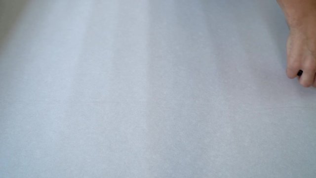 closeup male hands measure new wallpaper roll with measure tape on table indoor