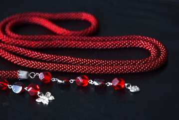 Lariat necklace red color with bead decoration on a dark background close up