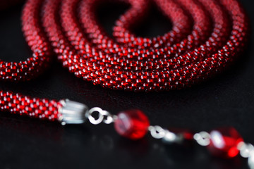 Lariat necklace red color with bead decoration on a dark background close up