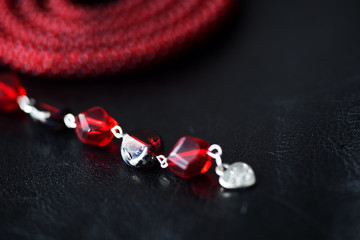 Lariat necklace red color with bead decoration on a dark background close up