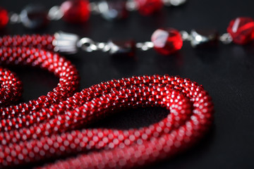 Lariat necklace red color with bead decoration on a dark background close up