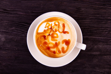 A cup with an inscription from caramel in coffee with milk