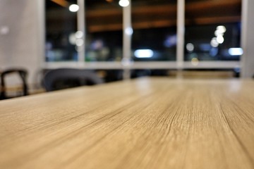 Blurred wooden table with chair and glass window in the night,warm and bokeh light