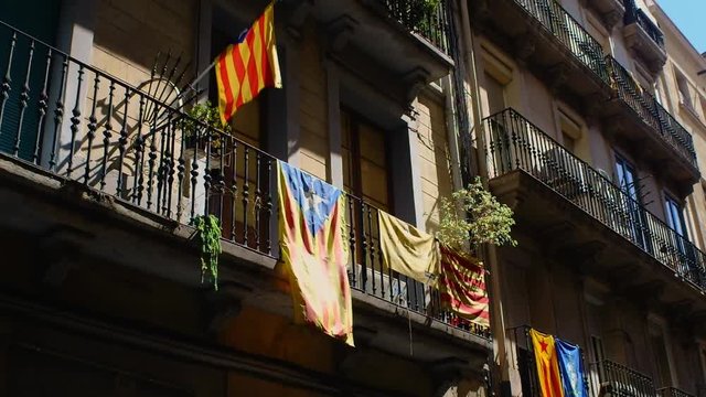 Several catalan independence flags hanging on the façade of several buildings and balconies in the Barcelona neighborhood of Gràcia.