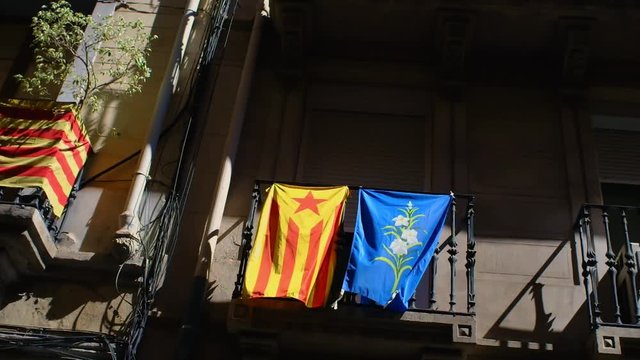 One Estelada side by side with a local neighborhood flag, hanging from a balcony on an old building in the Gràcia neighborhood of Barcelona