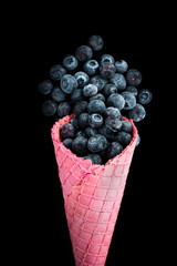 Pink wafer cone with frozen blueberry fruits. Ice cream