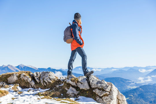 Female hiker standing on cliff against clear blue sky