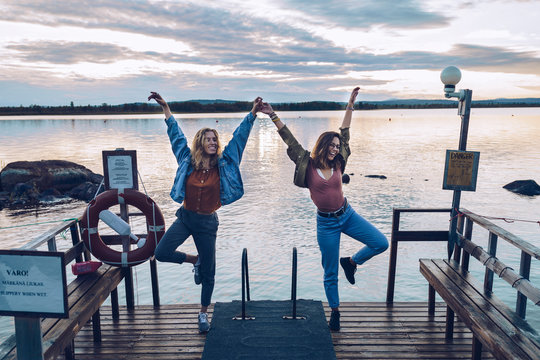 Fototapeta Two girl friends standing on one leg on a pier at Lake INari, Finland