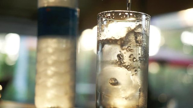 Water slowly pouring in glass. Cubes of ice in beverage. slow motion. 1920x1080