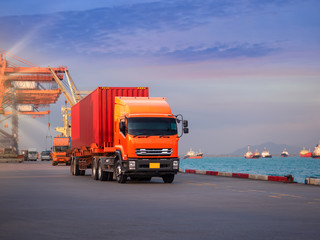 The container vessel  during discharging at an industrial port and move containers to container yard by trucks.