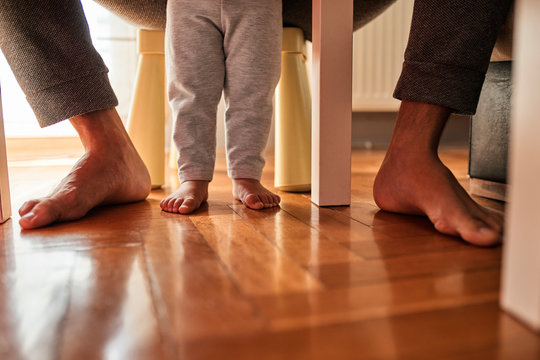 Father's and little daughter's feet barefoot on parquet