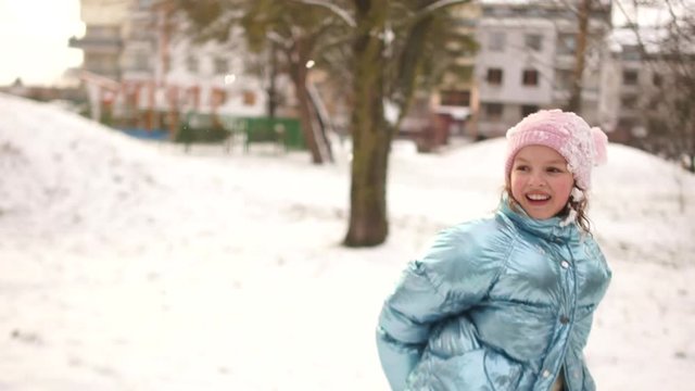 Father and daughter play snowballs. Both were dirty in the snow, disheveled and agitated. The girl wears a pink hat and silver jacket