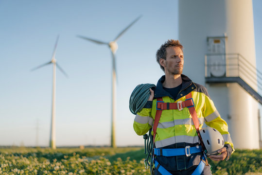 Technician standing at a wind farm with climbing equipment