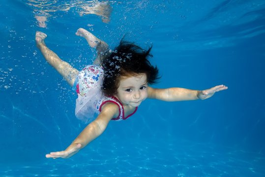Little girl learns to swim underwater in the pool, Ukraine, Europe
