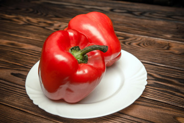 Two red peppers lying on a brown background 