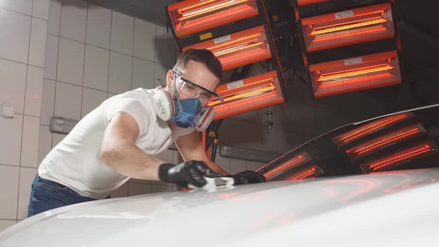 Master polishes the car in a car workshop