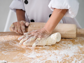 Kid hands in uniform preparing dough for pizza or bread, lifestyle concept.