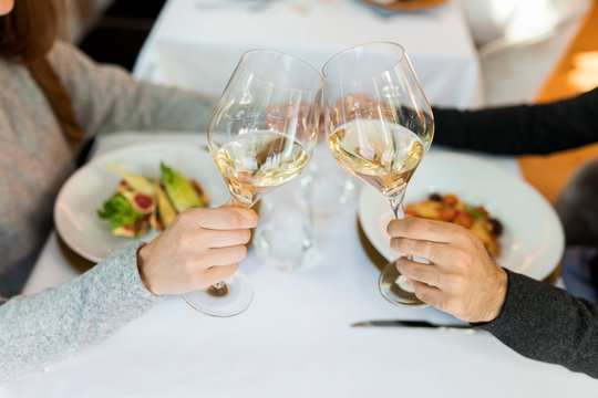 Close-up of couple clinking wine glasses in a restaurant